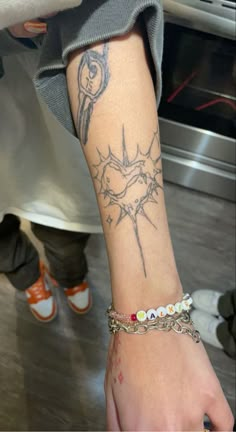 a person with a tattoo on their arm wearing a chain link bracelet and matching watch