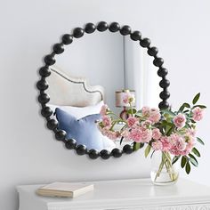 a vase filled with pink flowers sitting on top of a white dresser next to a mirror