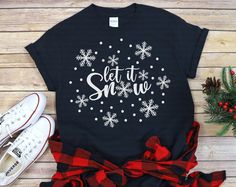 a t - shirt with the words let it snow written in white and red on black