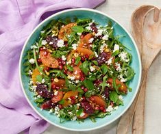 a salad with spinach, oranges and feta cheese in a blue bowl