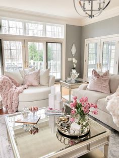 a living room filled with furniture and pink flowers on top of a glass coffee table