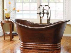 an old fashioned bathtub is in the middle of a wooden floor