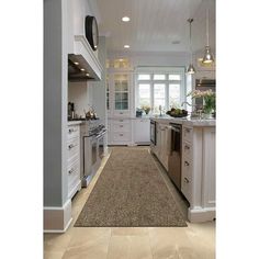 a large kitchen with white cabinets and an area rug on the floor in front of the stove