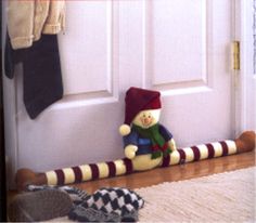 a teddy bear sitting on the floor in front of a door with stockings and mittens