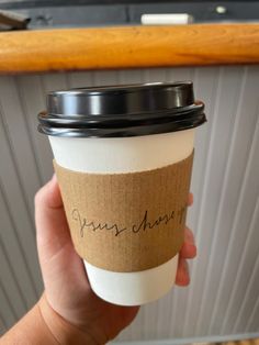 a person holding a coffee cup with writing on it