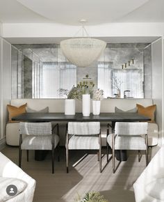 a dining room table with white chairs and a large mirror on the wall above it