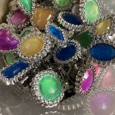 a bunch of colorful rings sitting on top of a glass plate with silver trimmings