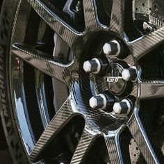 the wheels and rims of a car are covered in black carbon fiber with white spokes