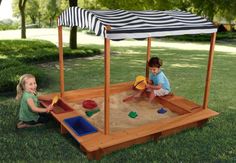 two children playing in a sandbox on the grass