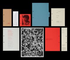 various folders and papers are arranged on a black surface, including one with an image of a man's face