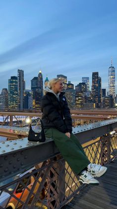 an older woman sitting on top of a bridge in front of a cityscape