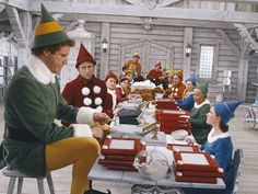 the elf is handing out gifts to the children at the table in front of them