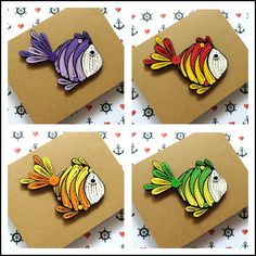 four different colored fish magnets sitting on top of a piece of brown cardboard paper