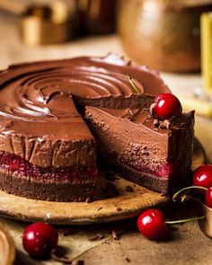 a chocolate cake with two slices taken out of it and cherries on the side