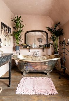 a bathroom with a claw foot bathtub and potted plants