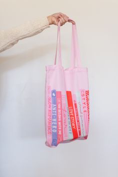 a person holding a pink tote bag with books on it