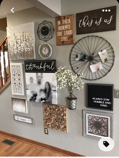 a wall with many pictures on it and some flowers in a vase next to the stairs