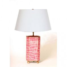 a pink lamp with a white shade on it and a gold frame around the base