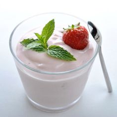 a glass filled with yogurt and a strawberry on top