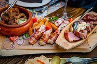 a wooden cutting board topped with different types of meats and veggies on it