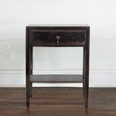 an old wooden table with a drawer on it's side, against a white brick wall