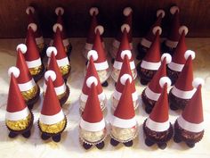 a bunch of cupcakes with santa hats on them are lined up in rows