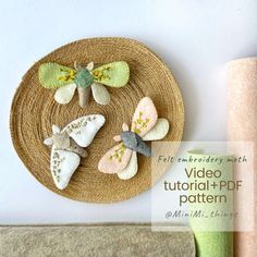 three felt butterflies on a woven plate next to a roll of toilet paper and a vase