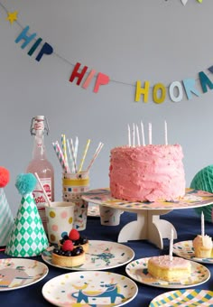 a table topped with lots of cakes and cupcakes next to bunting flags