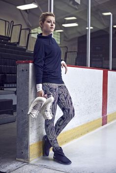 a young man leaning against a wall with his foot on the ground and wearing sneakers