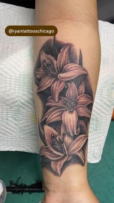 a woman's leg with tattoos on it and flowers in the middle of her arm