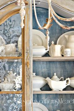 an old china cabinet with dishes and plates on it