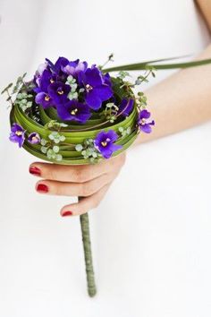 a woman's hand holding a bouquet of purple flowers