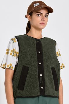 This Sherpa vest in khaki combines comfort and functionality. Crafted from soft, insulating fabric, it features a button front closure and two practical front pockets. The "THE TINY BIG SISTER" logo is subtly embroidered on the chest, adding a stylish touch to this versatile layering piece. Green Winter Vest With Buttons, Green Vest Outerwear For Layering, Green Layering Vest Outerwear, Winter Sleeveless Vest With Snap Buttons, Winter Layering Vest With Button Closure, Everyday Fall Vest With Button Closure, Sister Logo, Unlock Screen, Sherpa Vest