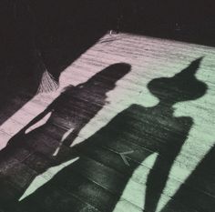 the shadow of two people standing next to each other in front of a wooden roof