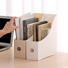 a laptop computer sitting on top of a desk next to a book holder filled with books