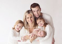 a man, woman and two children are posing for a family photo with their arms around each other