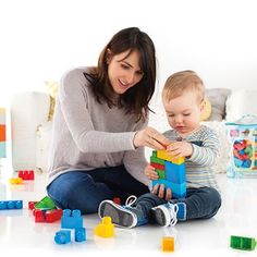 a woman and child playing with blocks on the floor