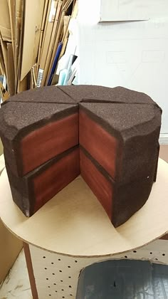 a large chocolate cake sitting on top of a table next to cardboard boxes and scissors