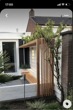 a wooden bench sitting in the middle of a yard next to a tree and bushes