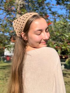 a young woman with long hair wearing a knitted headband in front of an apple tree