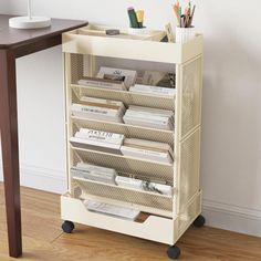 a book shelf with many books on it next to a wooden table and white wall