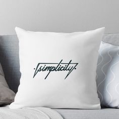 a white pillow with the word complicity in green on it sitting on a couch