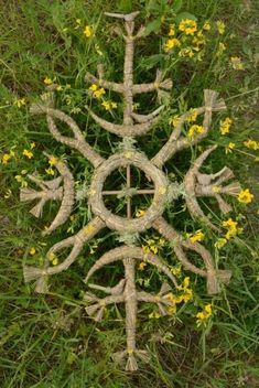 the top view of a garden decoration made out of branches and rope with yellow flowers