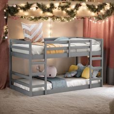 a bunk bed with two sets of mattresses and pillows on the bottom level, in front of a christmas tree