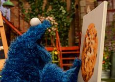 the sesame street cookie monster is looking at an image on a board with his eyes closed