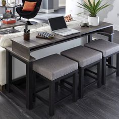 a laptop computer sitting on top of a table next to two stools and a plant