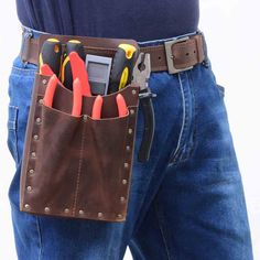 a man is holding a tool belt with many tools in it and his pants are blue