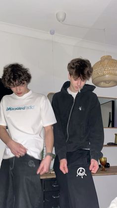 two young men standing next to each other in front of a table with food on it