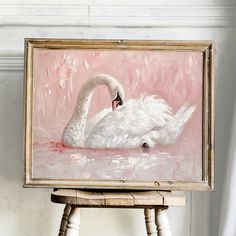 a white swan sitting on top of a wooden table next to a pink wall and floor