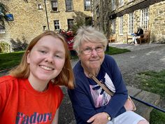 an older woman sitting next to a younger woman on a bench in front of a building